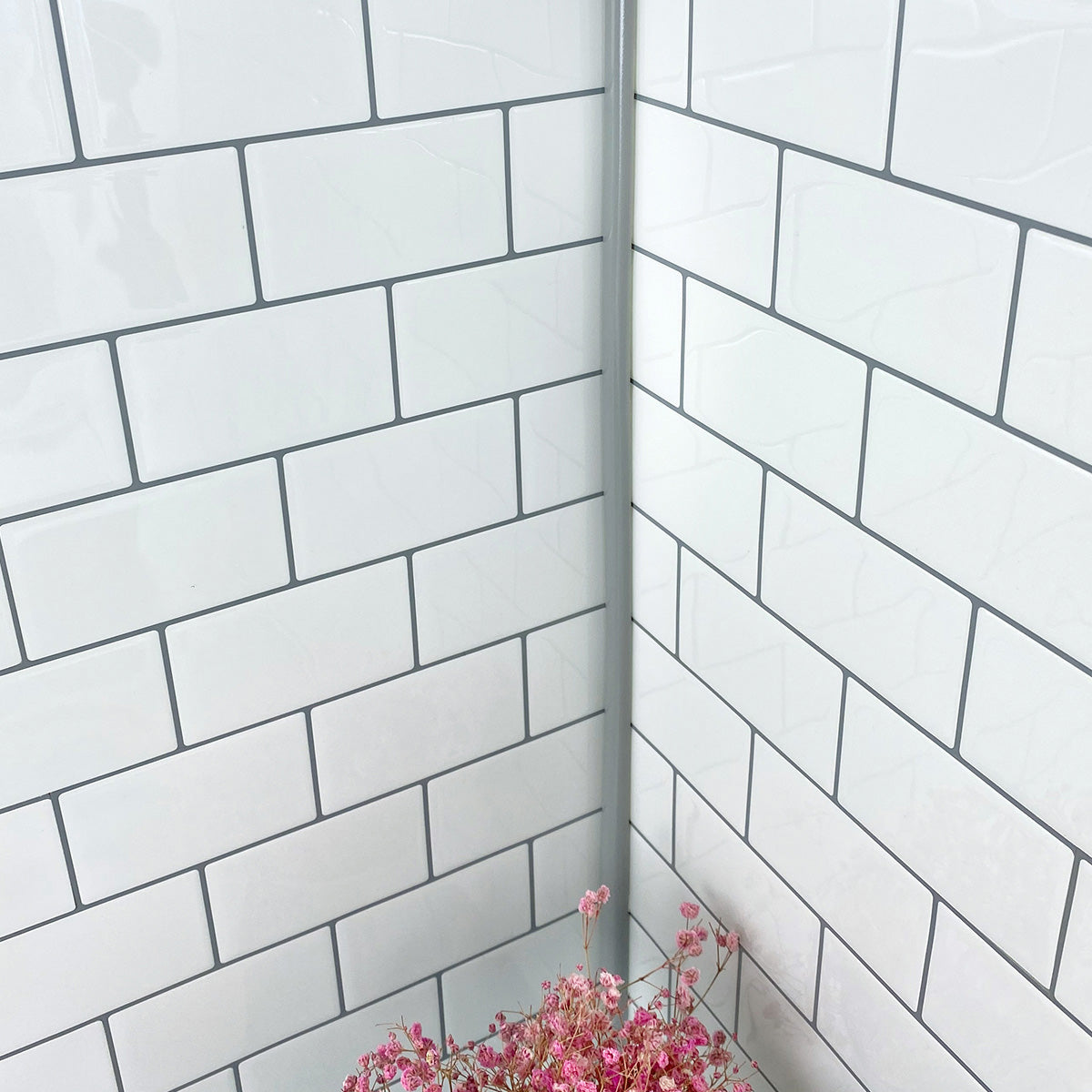 Grey edge trim in corner of white subway tiles with grey grout