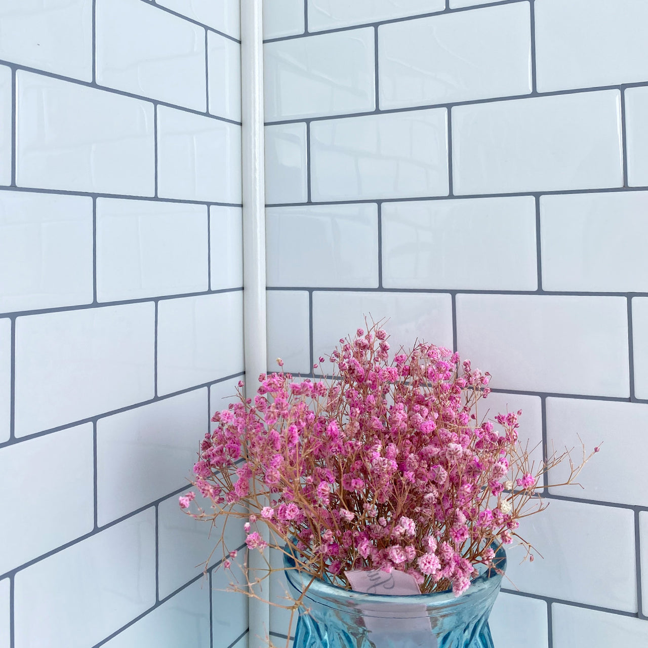 White edge trim in a corner of white subway tiles